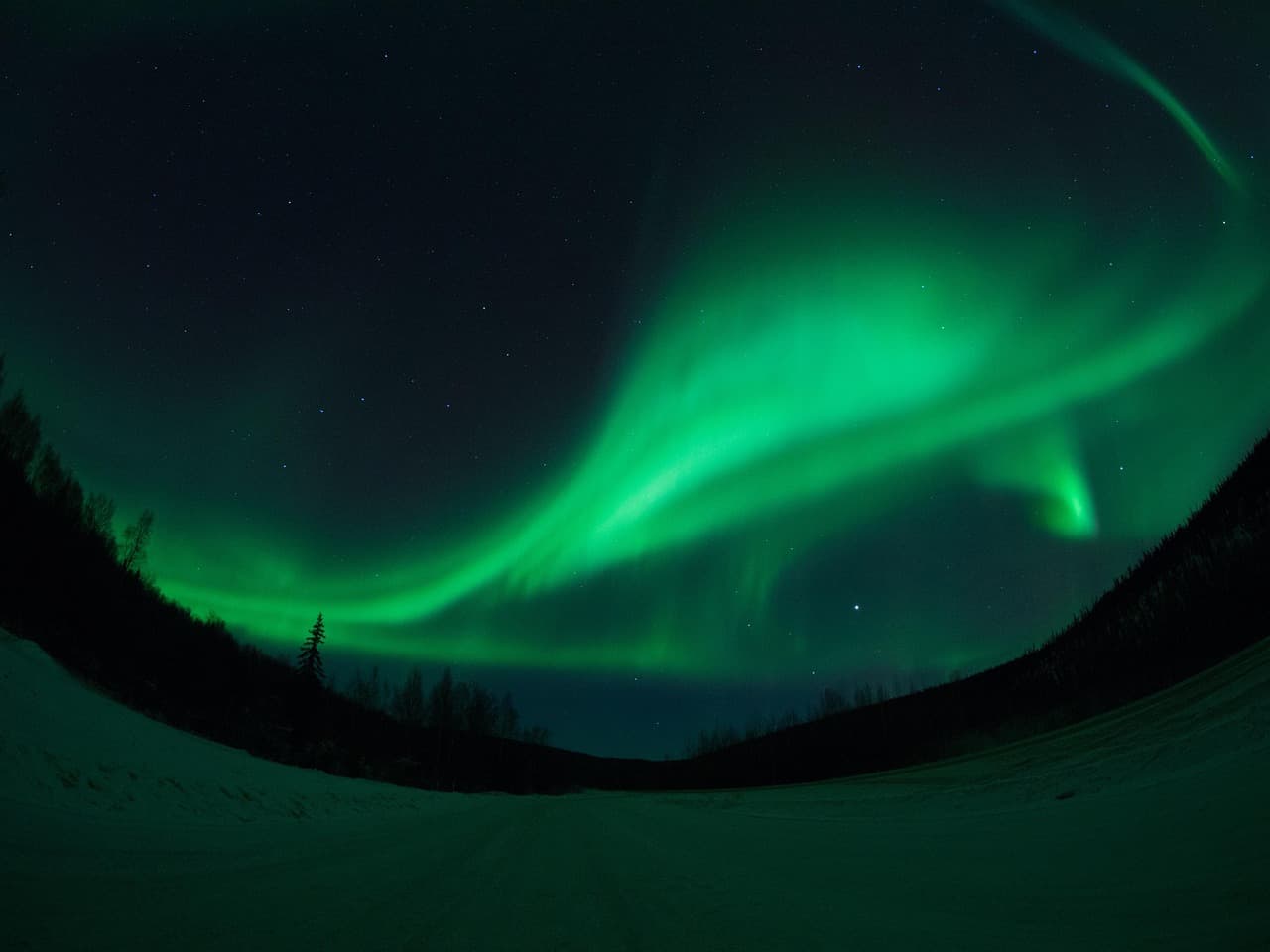 Aurora borealis over snowy road in Fairbanks, Alaska at night