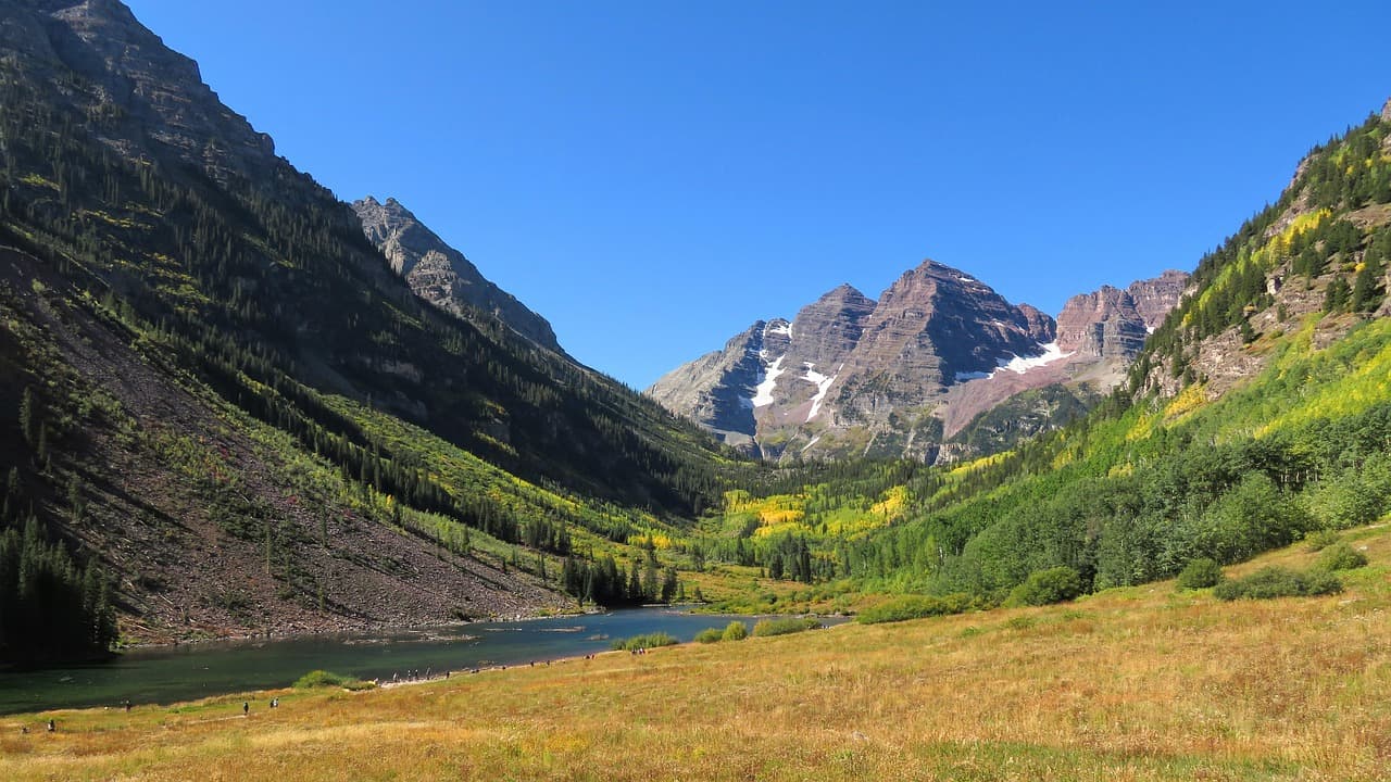Autumn reflection of Maroon Bells in a serene Colorado lake surrounded by mountains